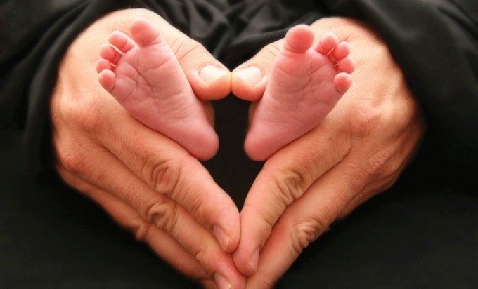 parent holding baby's feet in shape of heart